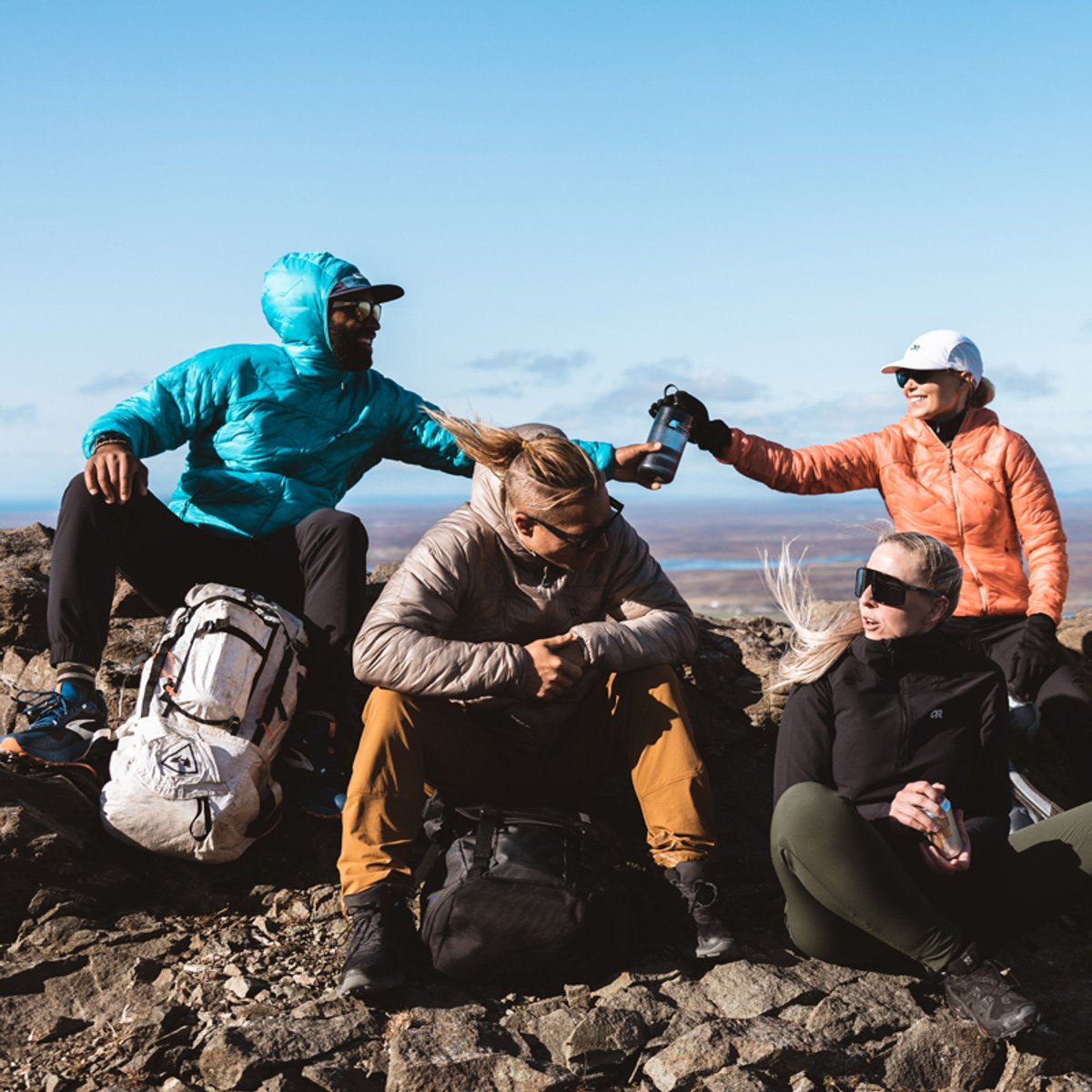 A group of friends rests at a mountaintop, wearing Ferrosi gear.