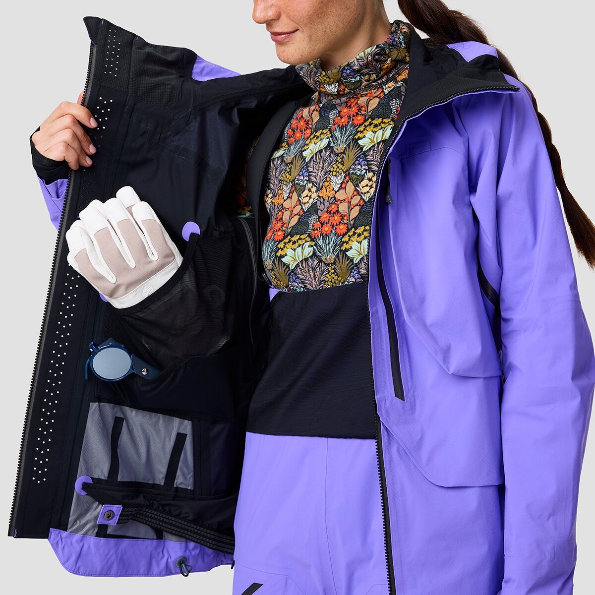 Person wearing Cottonwoods LT ski jacket holding one side open to reveal internal pockets and minimal powder skirt.