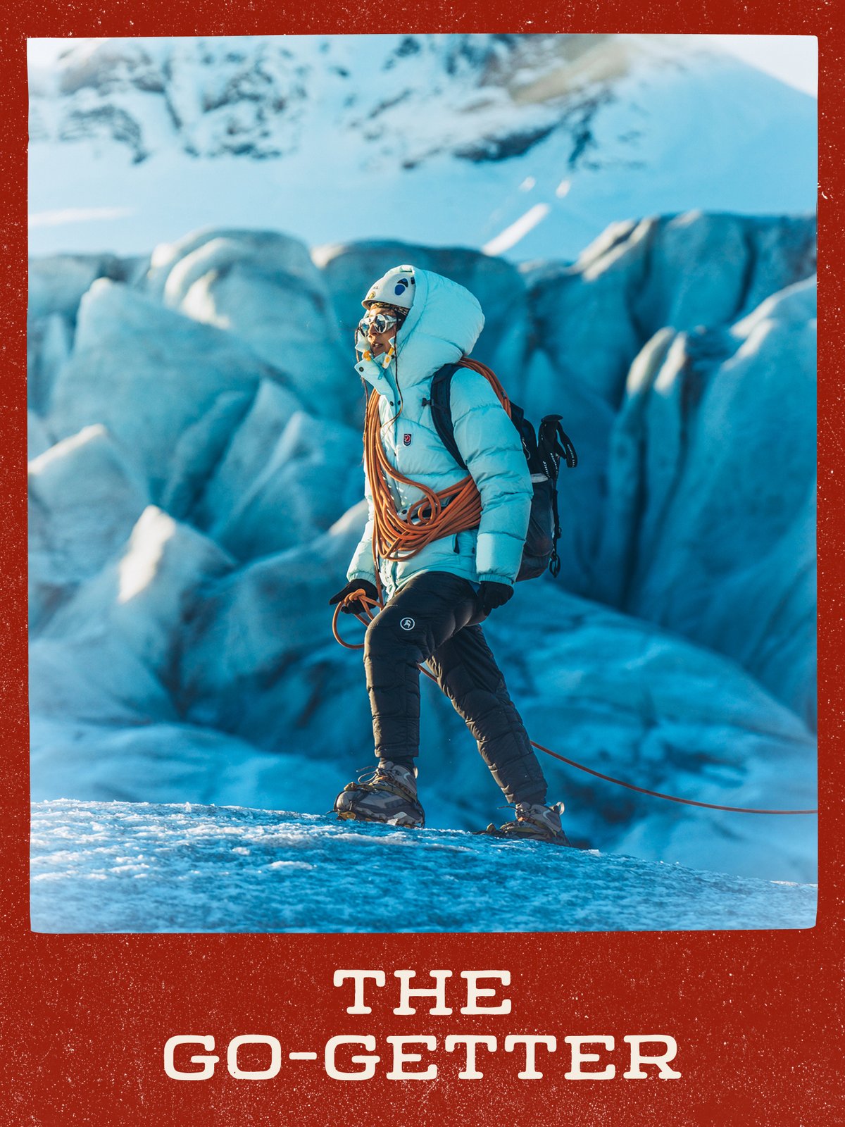 Climber in a helmet and crampons with a coiled rope over one shoulder, walking a glacier with blue ice formations behind: “The Go-Getter.”