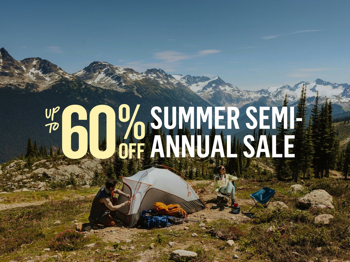 Up to 60% off Summer Semi-Annual Sale — camping gear, tents and hiking equipment. Campers with tent in alpine meadow with snow-capped mountains.
