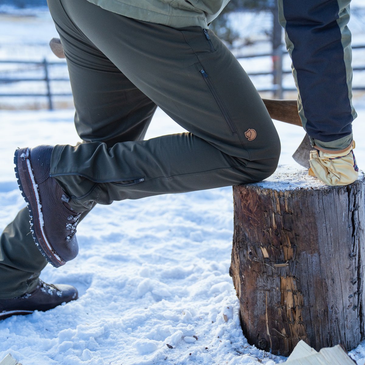 A man kneels on a log.