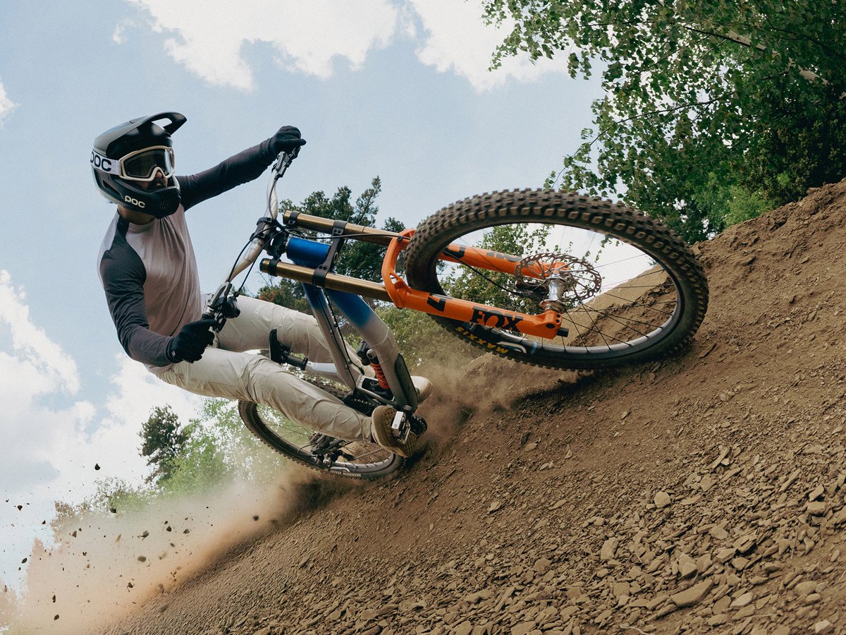 A mountain biker kicks up some dirt as they make a tight turn.