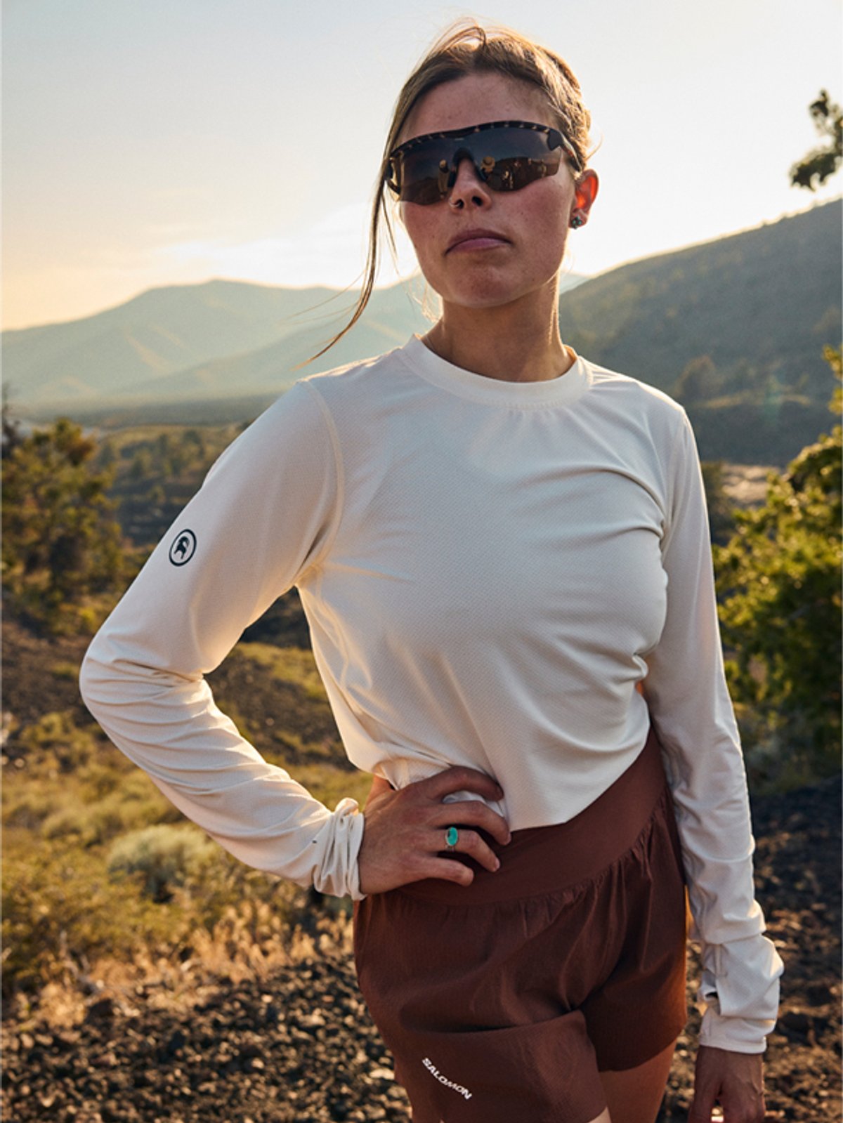 A woman wearing the Tahoe Sun Hoodie poses in front of trail