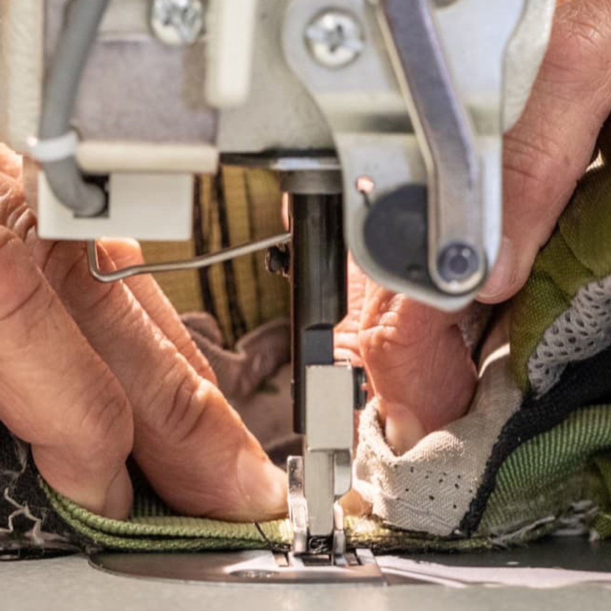 A closeup of hands using a sewing machine