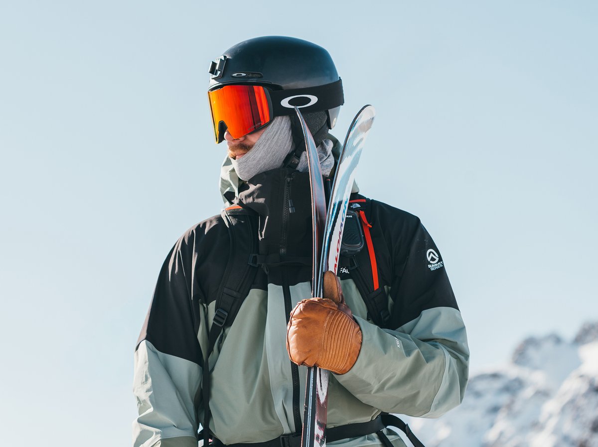 A skier looks to their left holding a pair of skis.