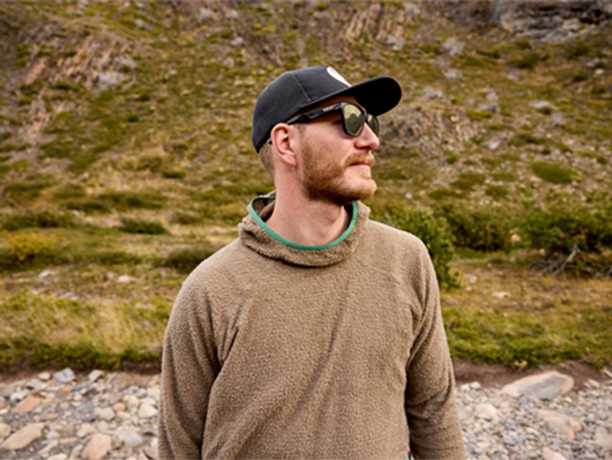 Person wearing fleece jacket with ahat and sunglasses staring into the distance.