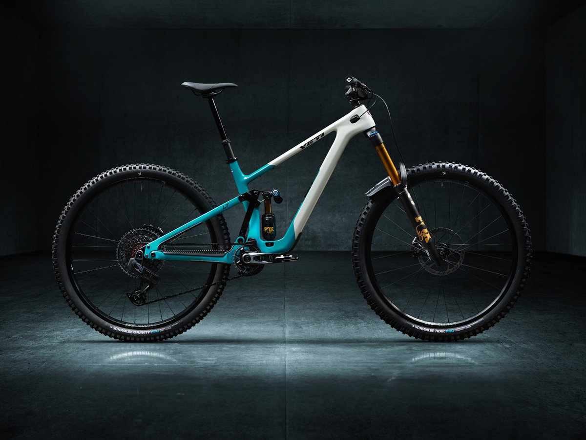 A teal and white mountain bike in a stark studio.