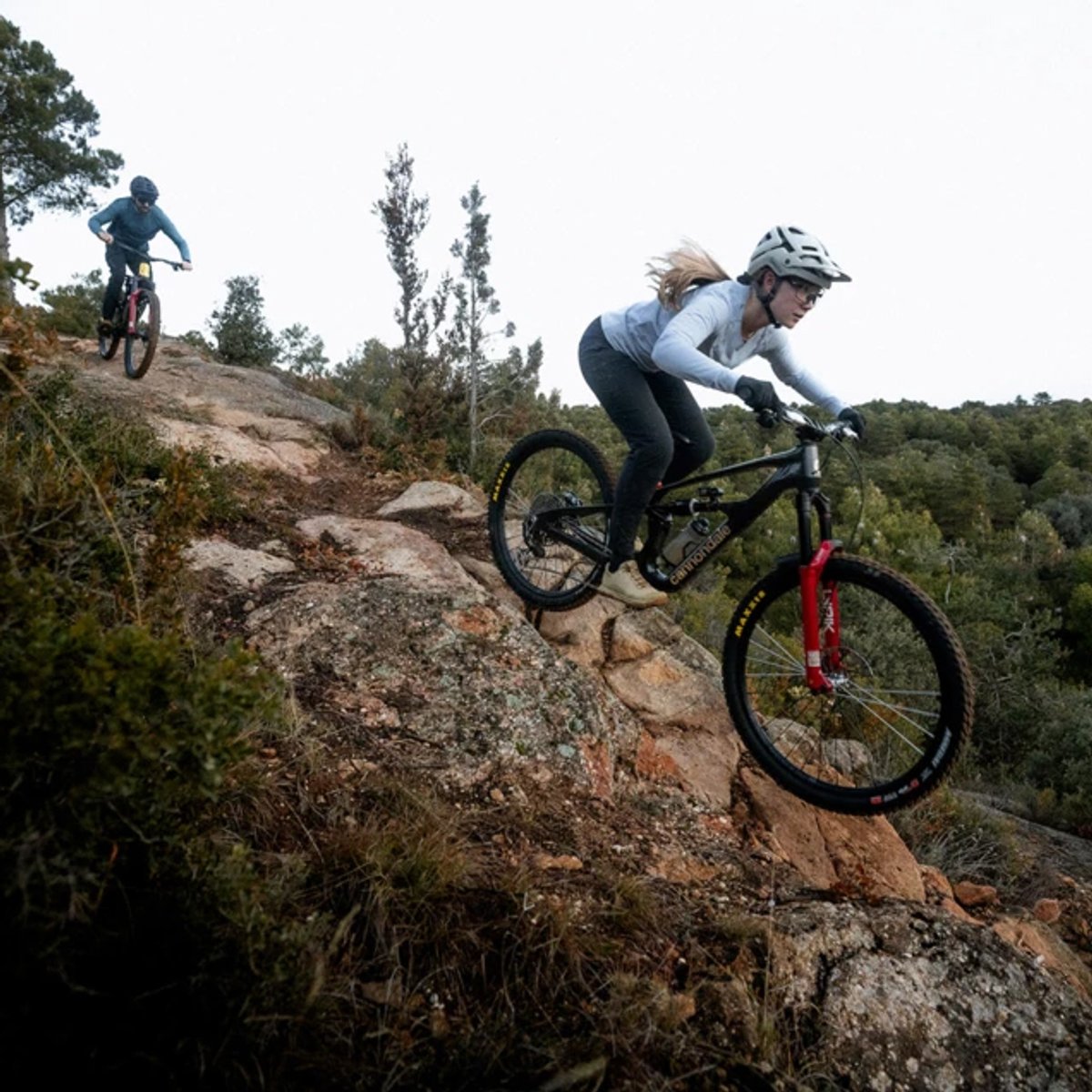 Two bikers make their way down a rocky path