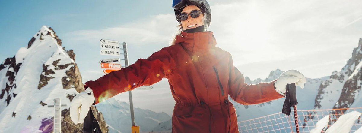 Skiier standing at a trail devide looking happy