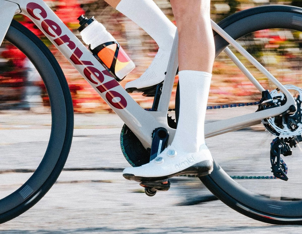 Close-up of road cyclist pedaling stroke on Cervélo road bike showing drivetrain and cycling shoe detail on city pavement