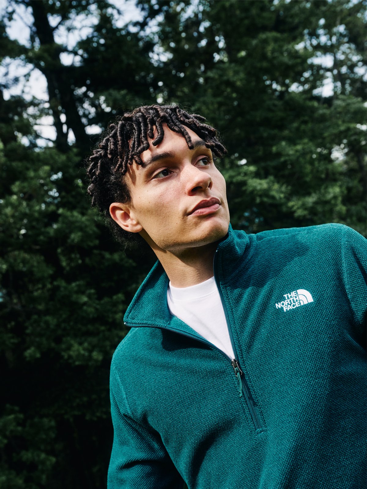 A man wears The North Face quarter zip fleece against the backdrop of a forest.