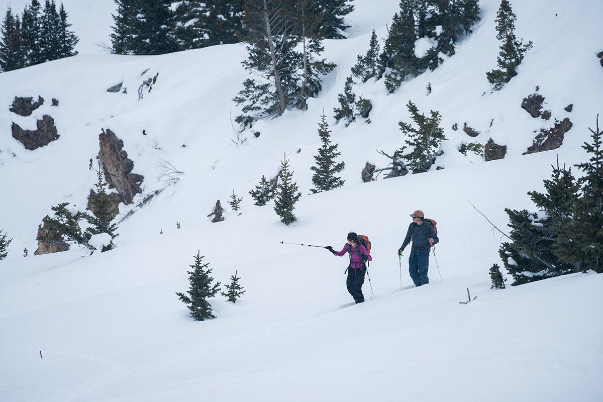 Two skiers skining uphill on a snowy mountain face.