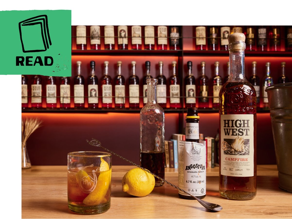 A bar countertop displays an old fashioned in a rocks glass, a bottle of High West, a lemon, and bitters. A green flag includes an illustration of a book and the word “read.”