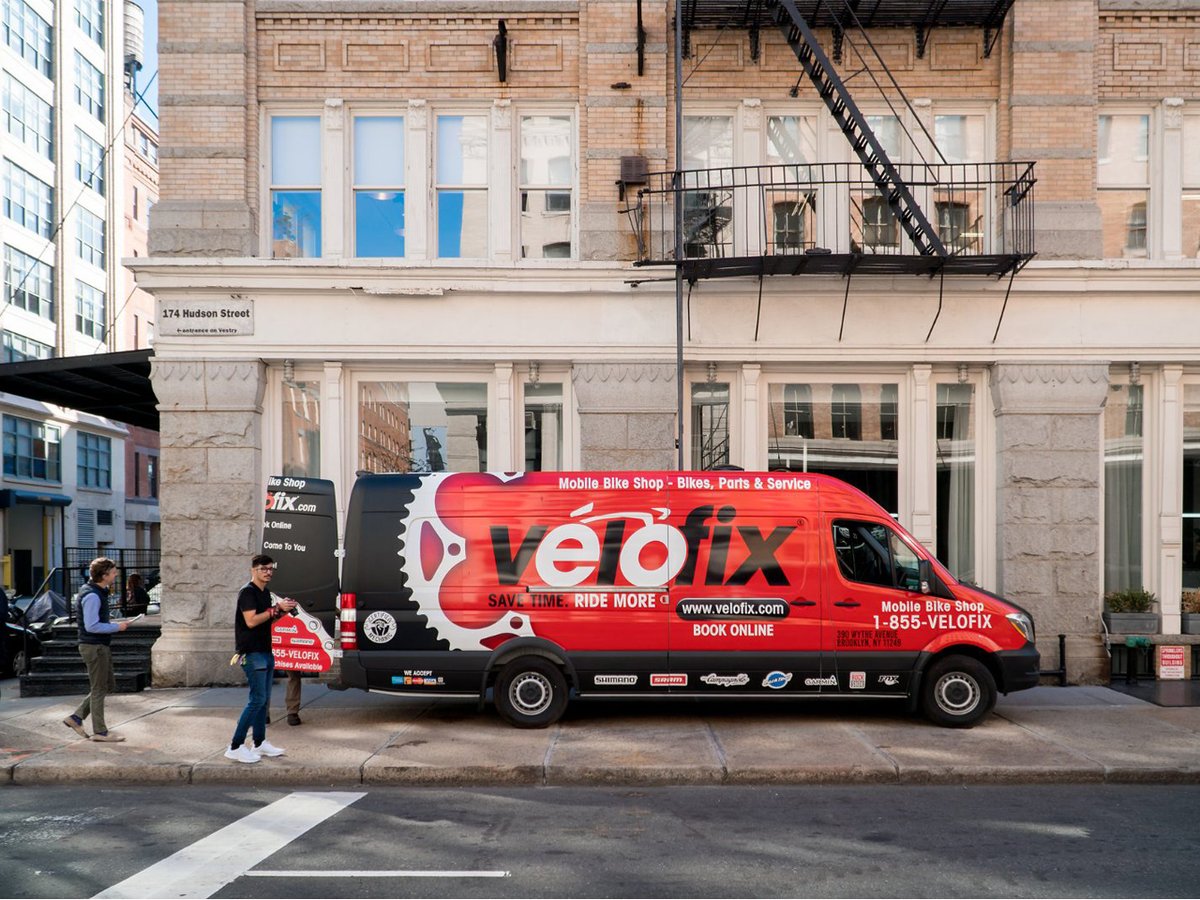 A Velofix van is parked on the sidewalk of an apartment building.