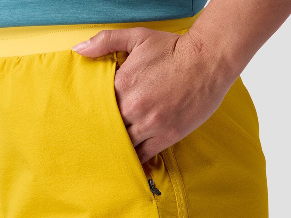 Close-up of hand resting in zippered pocket of shorts.