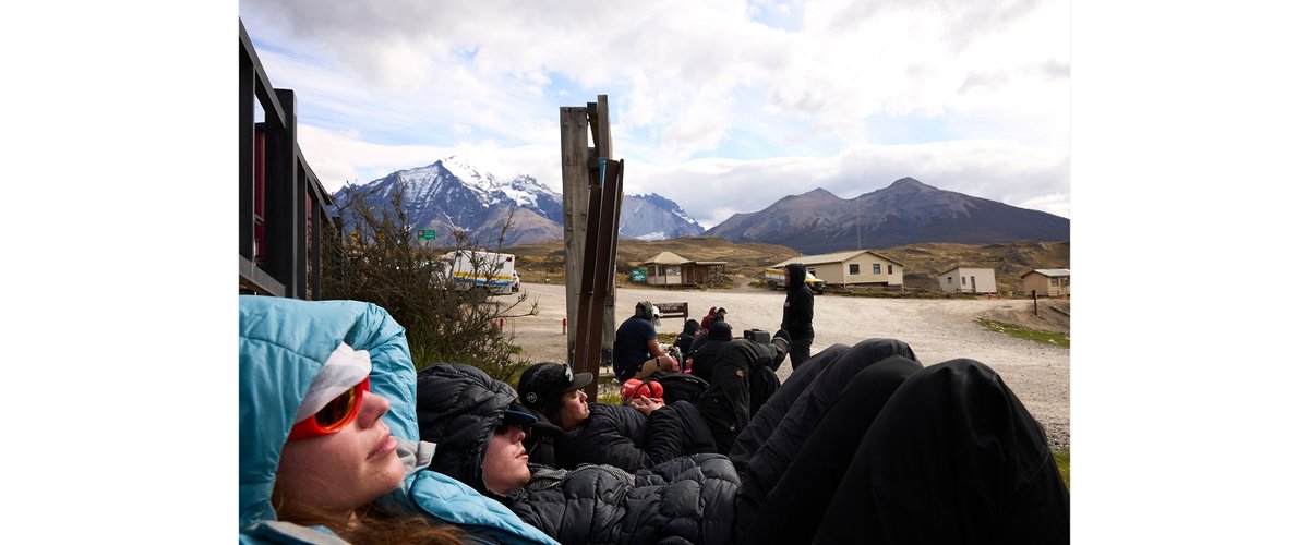 People wrapping in puffy jackets wait for a bus in Santiago.