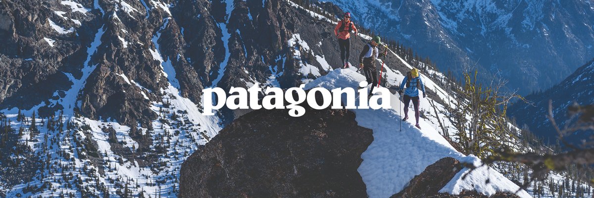Three trail runners traverse a snowy ridgeline above a steep mountain valley, trekking poles in hand, Patagonia logo overlaid.