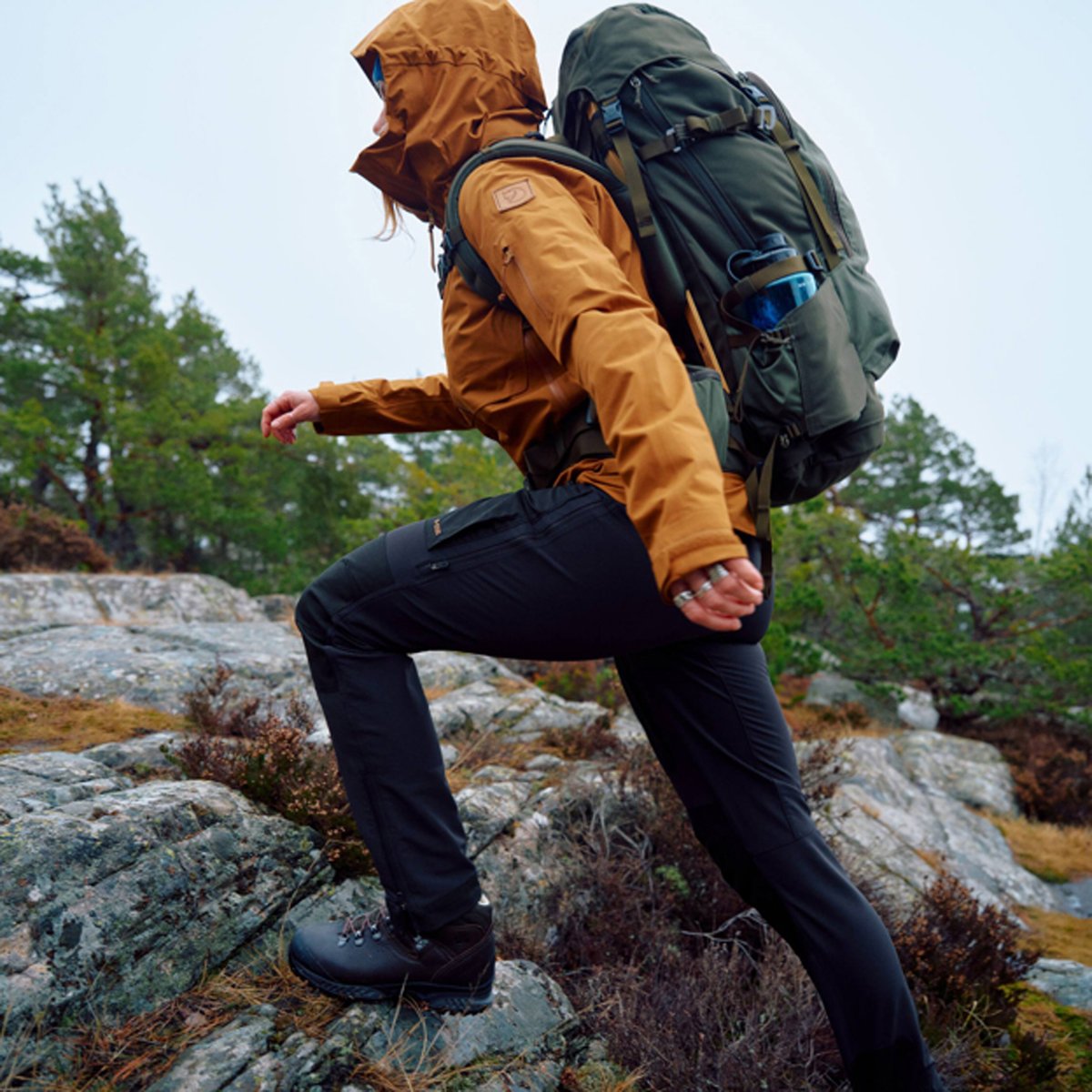A woman hikes across a rocky terrain, wearing Fjallraven Keb gear.