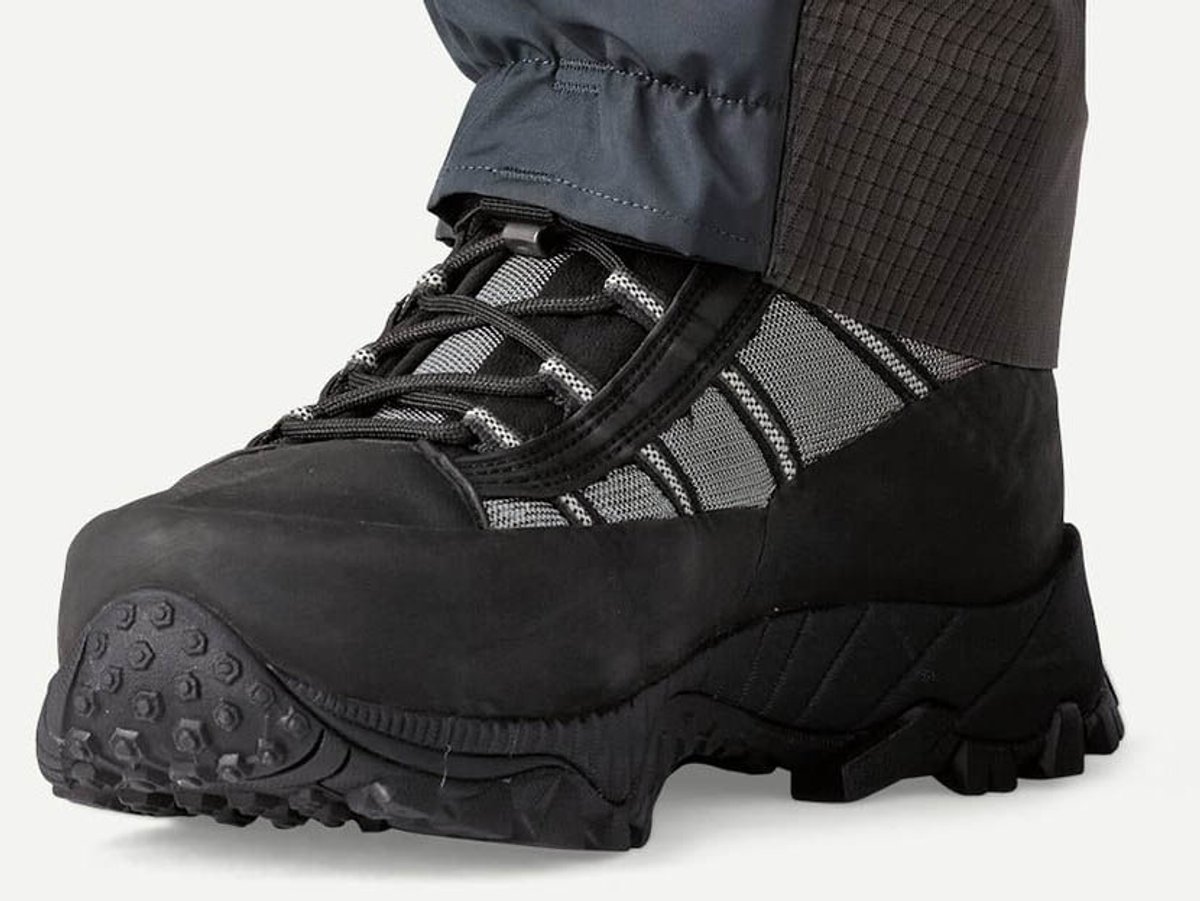 Boot shown on-foot with pant cuff over the collar, black toe cap and lugged sole visible against a white background.
