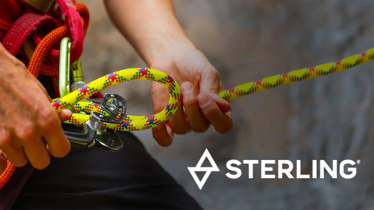 Person holding a colorful yellow, red, and blue Sterling climbing rope with a carabiner attachment for outdoor rock climbing and rappelling activities.