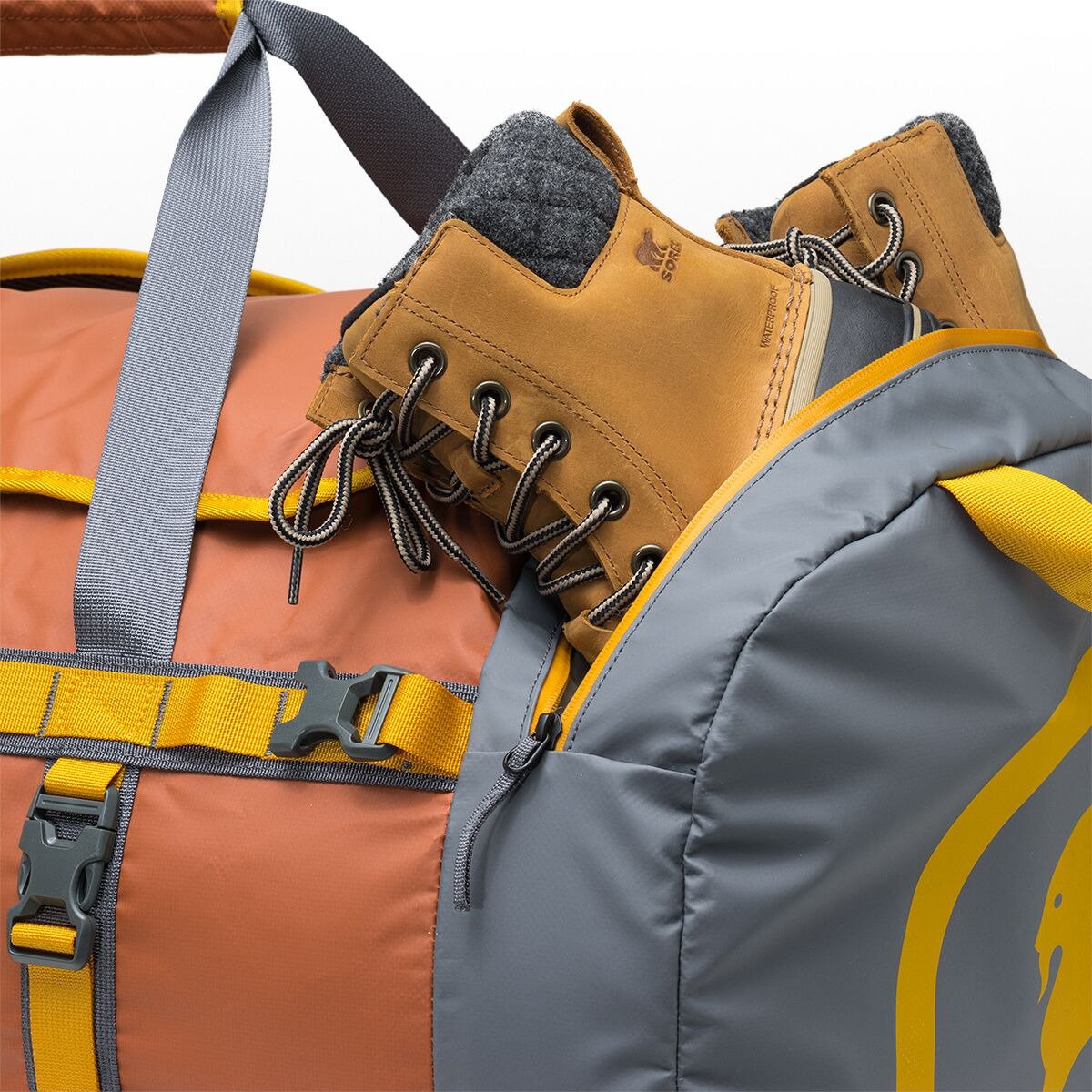 Close-up of a duffel bag’s waterproof end cap pocket holding a pair of tan snow boots.