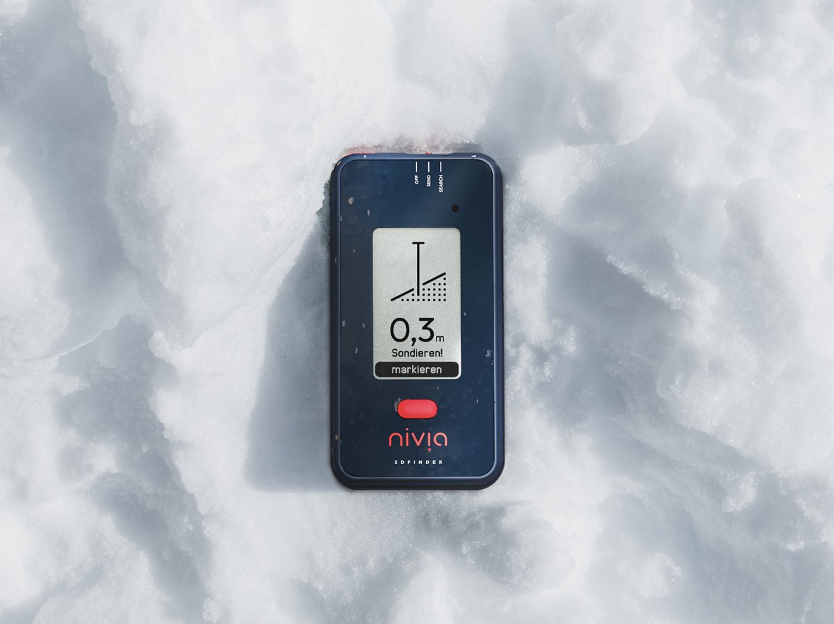 Nivia 3D Finder avalanche beacon displaying a search signal on its screen, resting in snow.