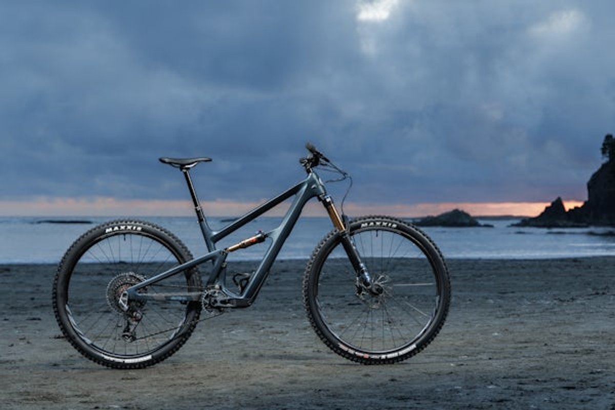 Bike standing on beach at sunset.