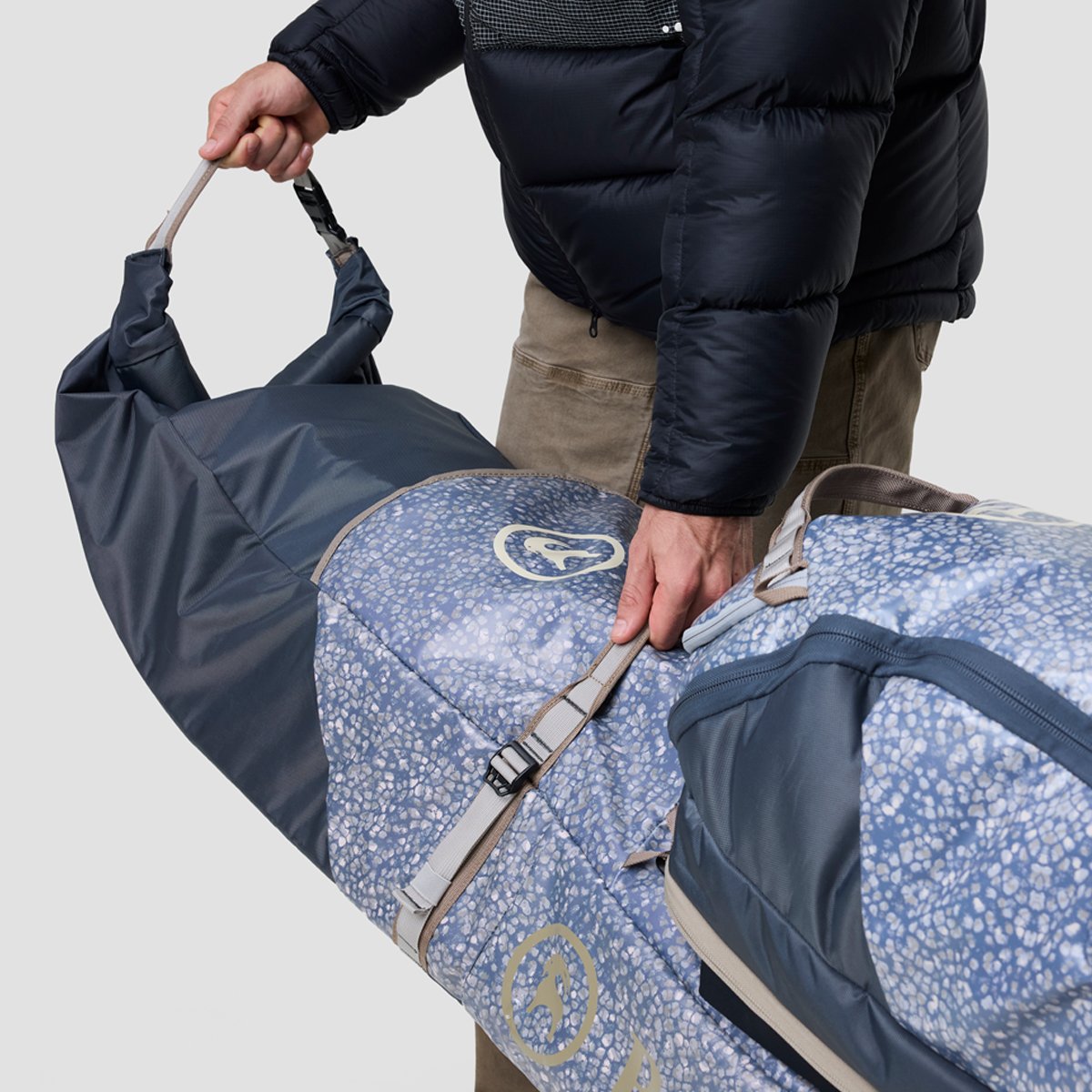 A closeup of the reinforced straps on the Double Ski & Snowboarding Rolling bag, highlighting the strap stitched down to the bag, plus two heavy-duty barracks at the base of the side straps, plus reinforced handle construction.