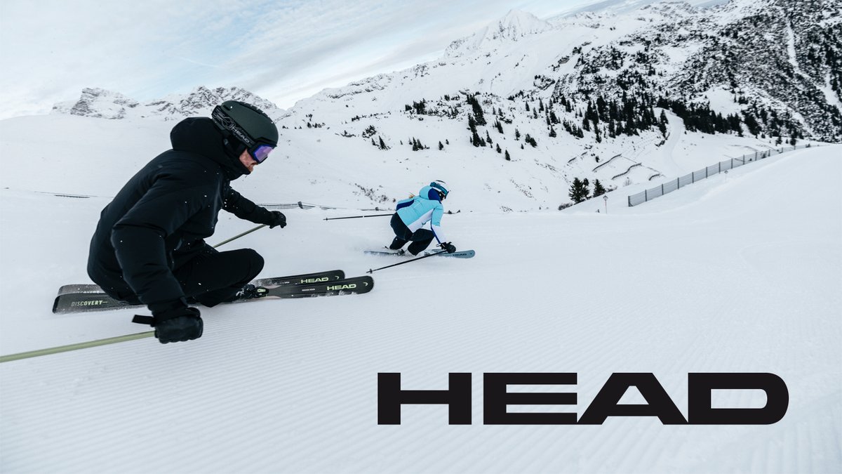 Adult  in black gear demonstrating proper skiing technique while guiding a child in blue jacket down snowy alpine slope with HEAD skis.