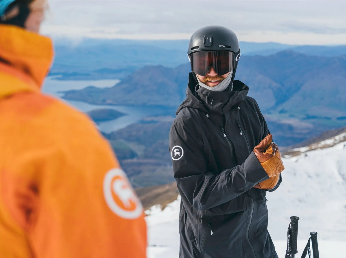 Two skiers talk on top of a mountain