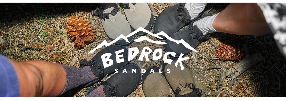 Top-down view of closed-toe sandals in a circle on a forest floor with pinecones, featuring the Bedrock Sandals logo.