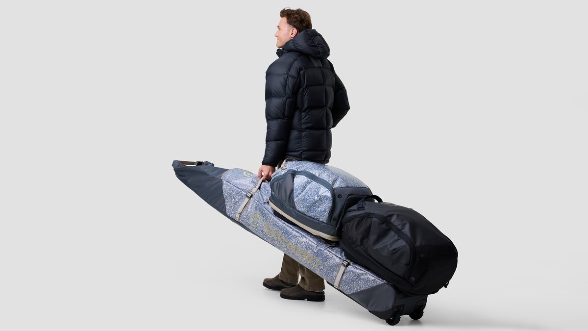 A person carrying the Ski & Snowboard rolling Bag G2 stands against a white background.
