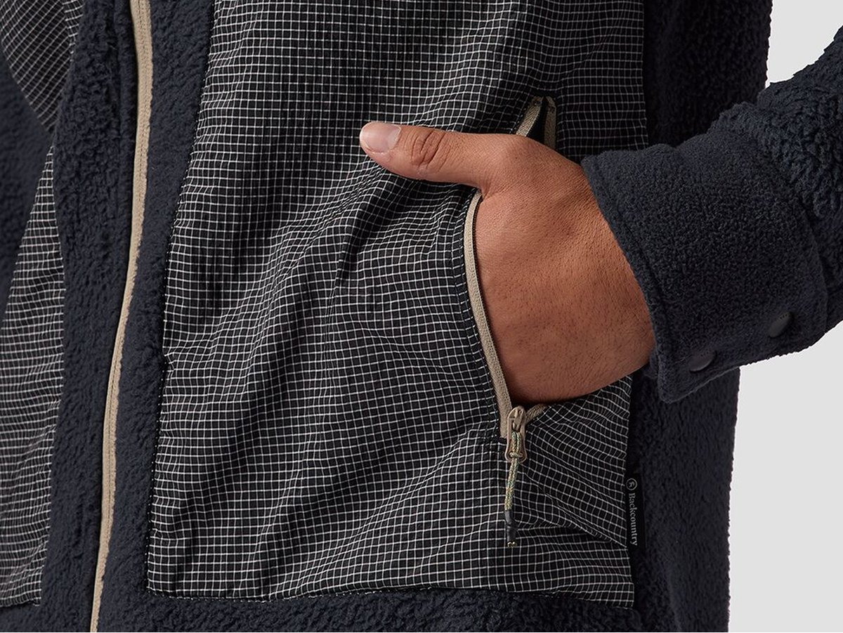 Close-up of a hand sticking out of a zippered pocket on black fleece jacket.