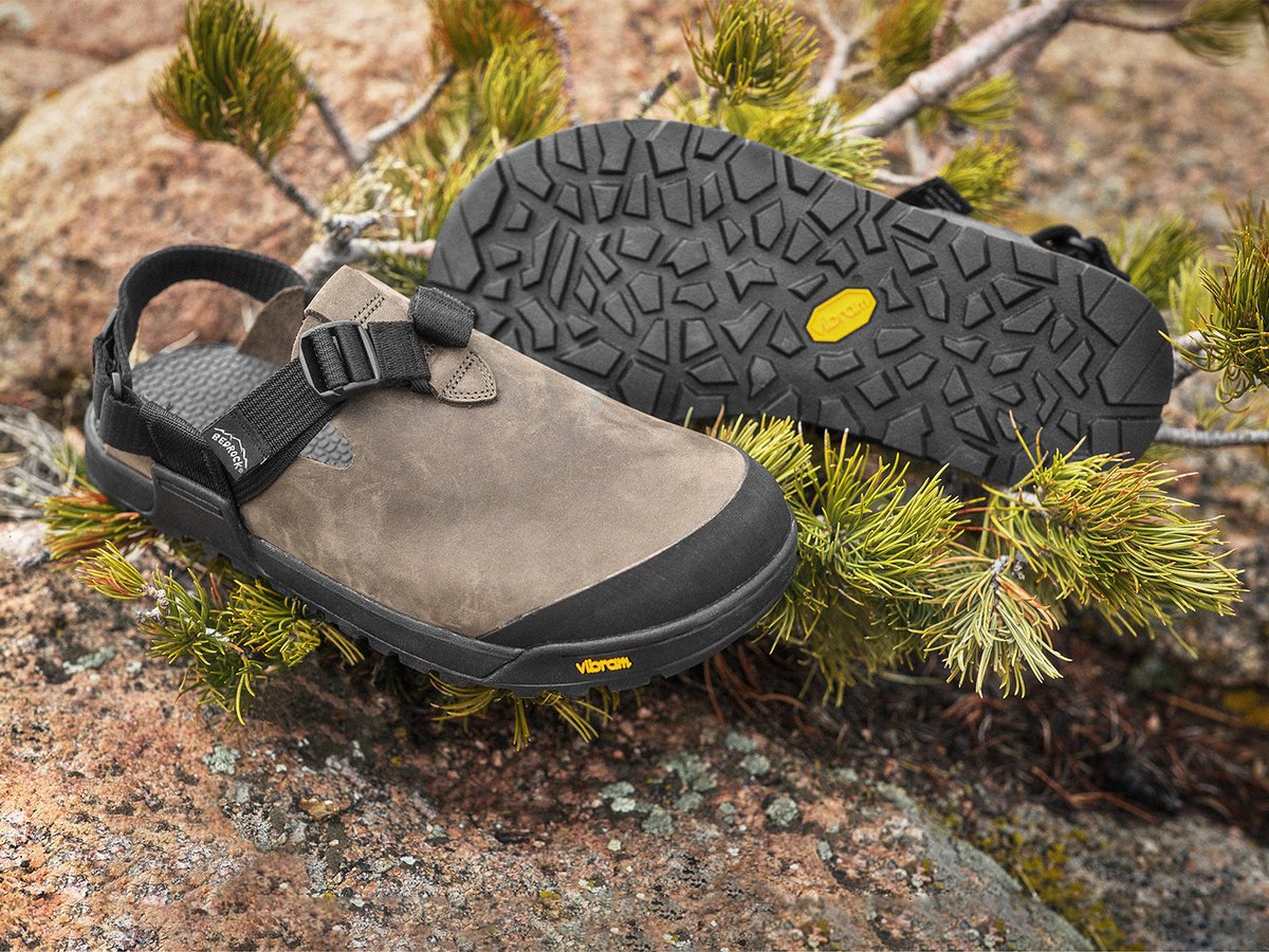 Bedrock Mountain Clog in gray nubuck shown from side and sole on rocky terrain with pine branches