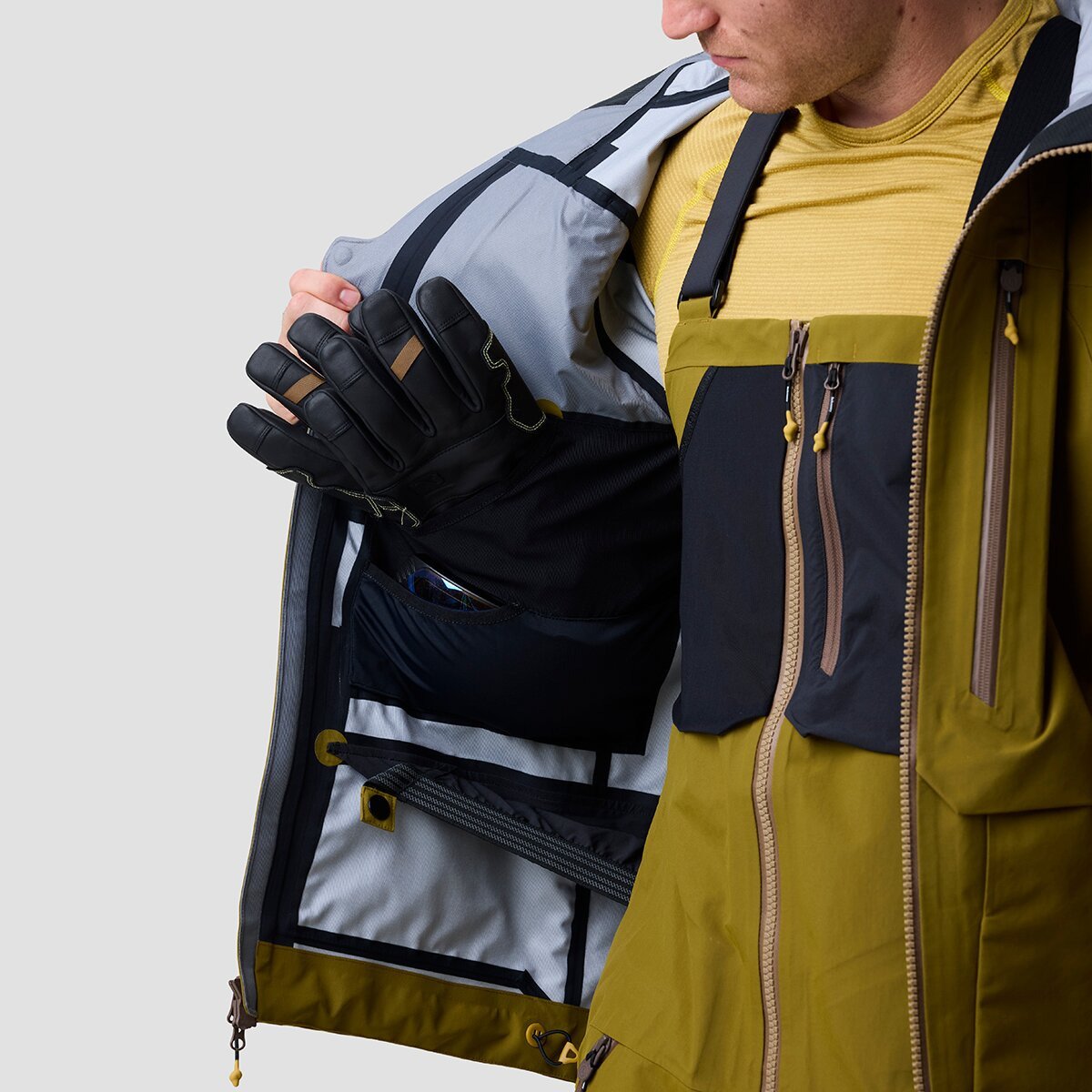 Person wearing Cottonwoods ski jacket with one side held open to see internal mesh pockets and low profile integrated powder skirt.