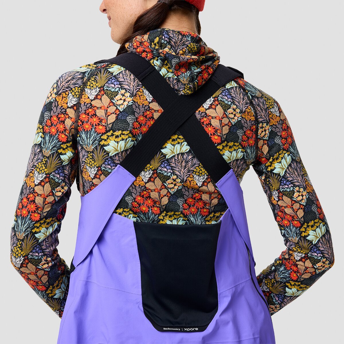 Person wearing ski bibs pictured from behind showing stretch panel at center back.