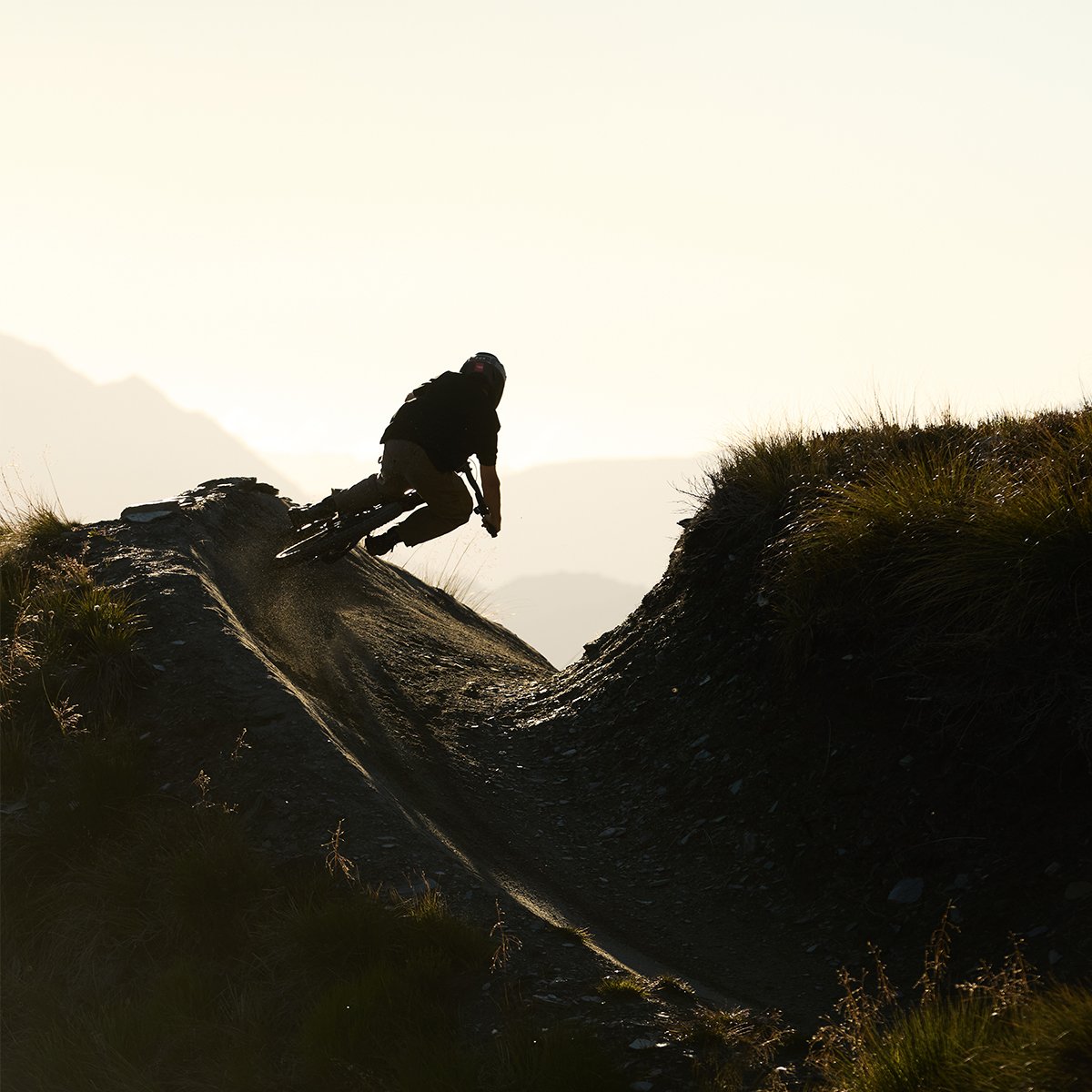 Rider shilouhetted against the sky riding around a sharp turn on the Sants Cruz Nomad Bike.