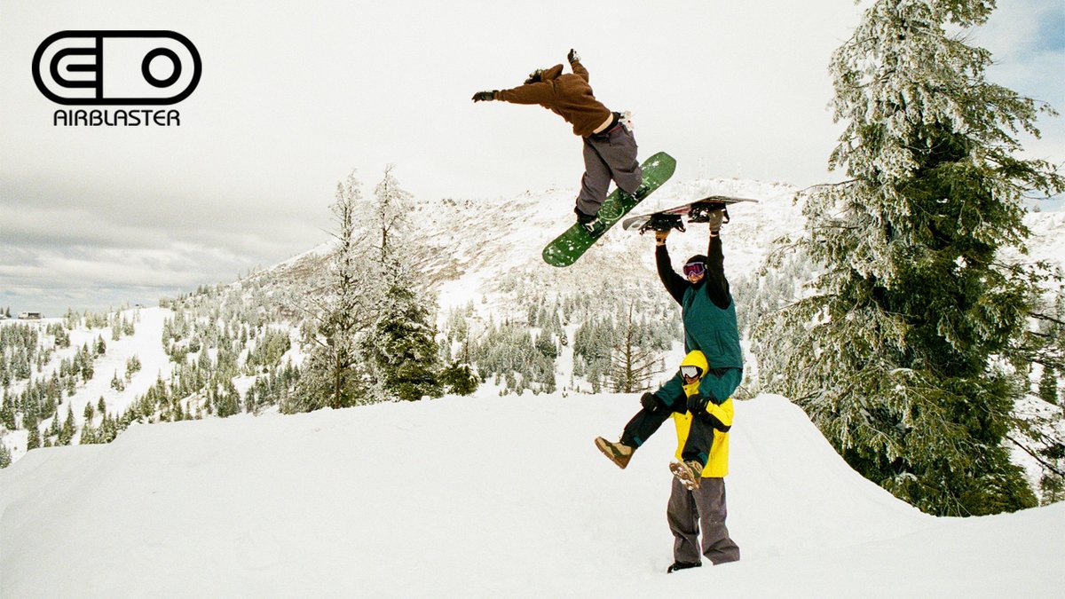 Three snowboarders perform tricks on a snowy mountain slope with forested peaks in the background, showcasing winter sports action and outdoor adventure gear.