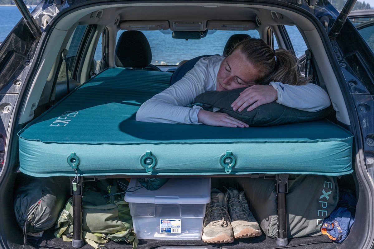 Woman sleeping comfortably in car trunk on top of the MegaMat. 