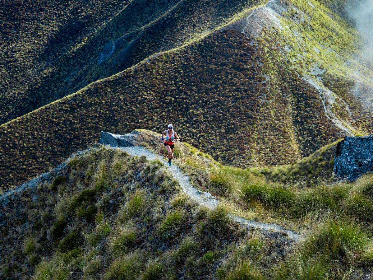 A person runs across a rocky mountain ridge.