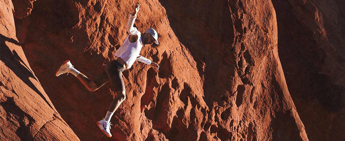 Trail runner jumping down a red rock face wearing Nike ACG Zegama Trail Shoe.