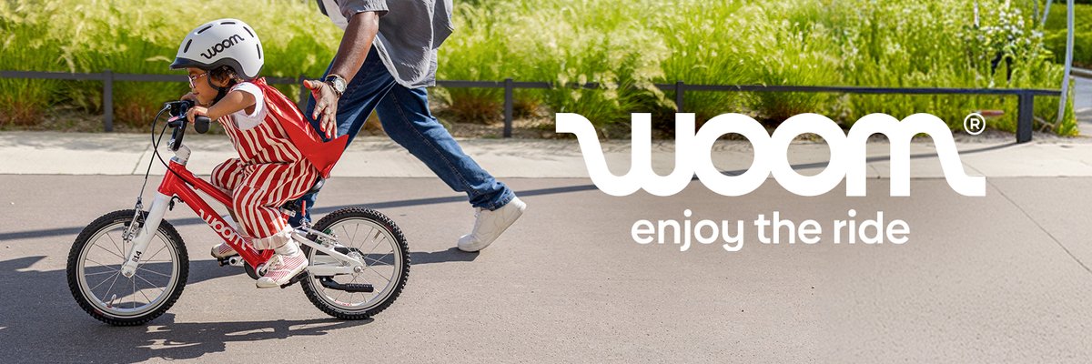 A kid rides a bike with an adult supporting.