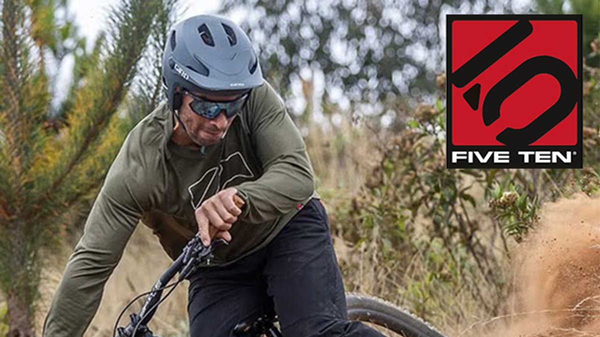 A mountain biker wearing a helmet and sunglasses leans into a dusty turn on a trail, with the Five Ten logo in the corner.