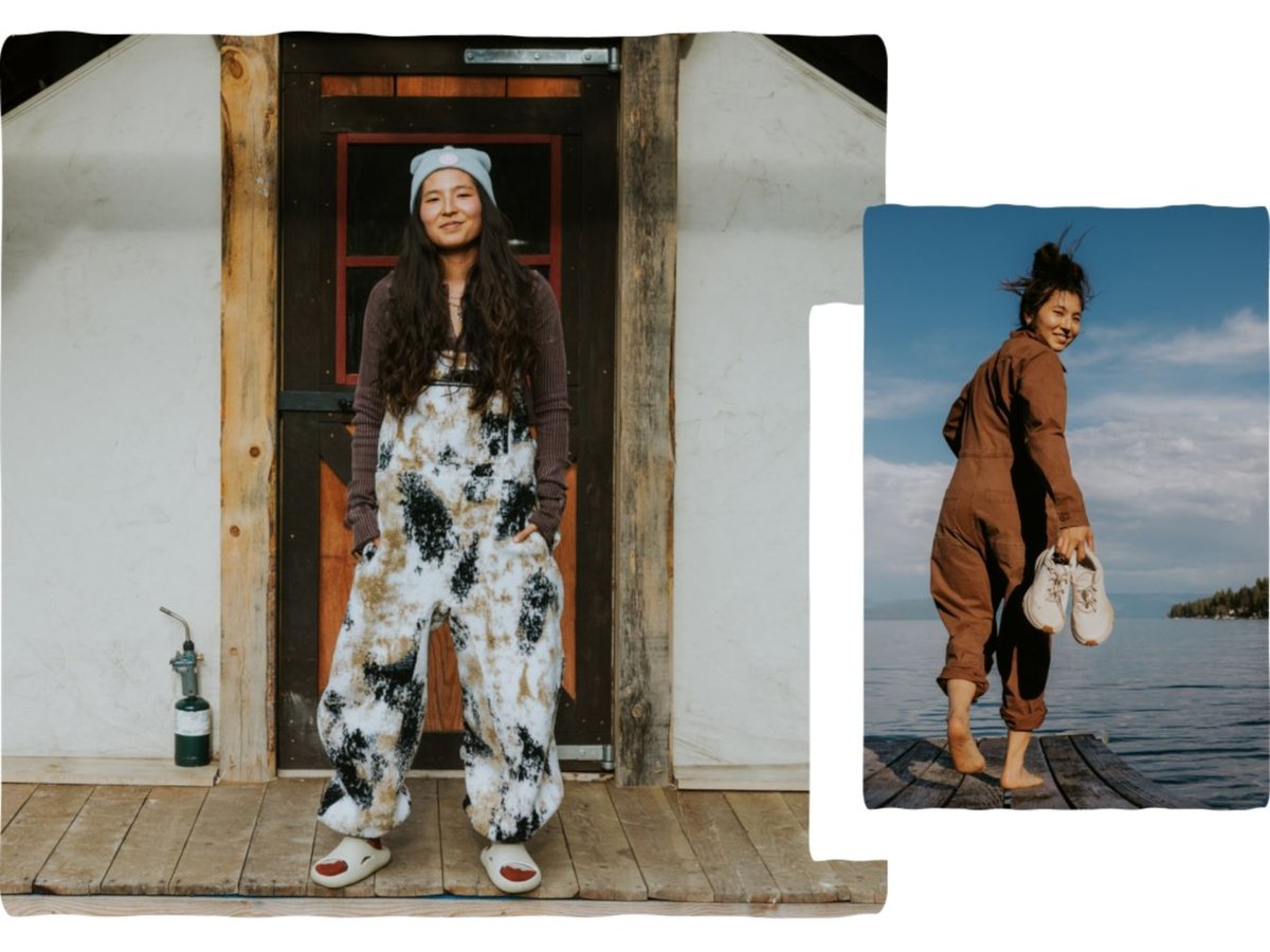 A person stands in front of their log cabin.