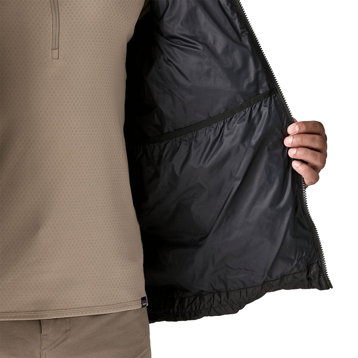 Person holding black Fitz Roy jacket open to show large elstic drop pocket on the inside.