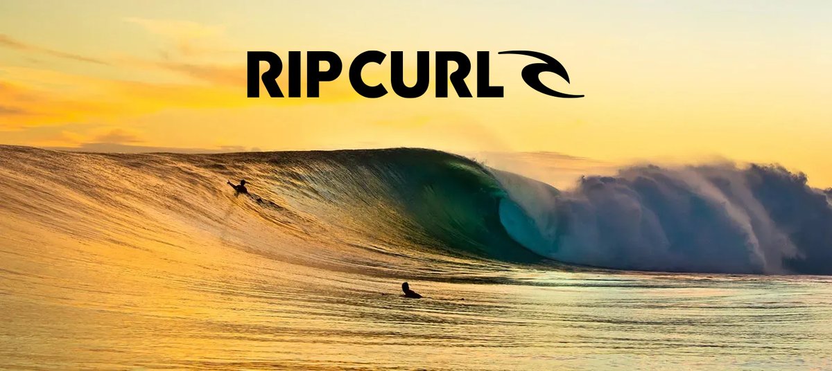 Surfer riding a massive barrel wave at sunset with golden light illuminating the ocean spray and foam.