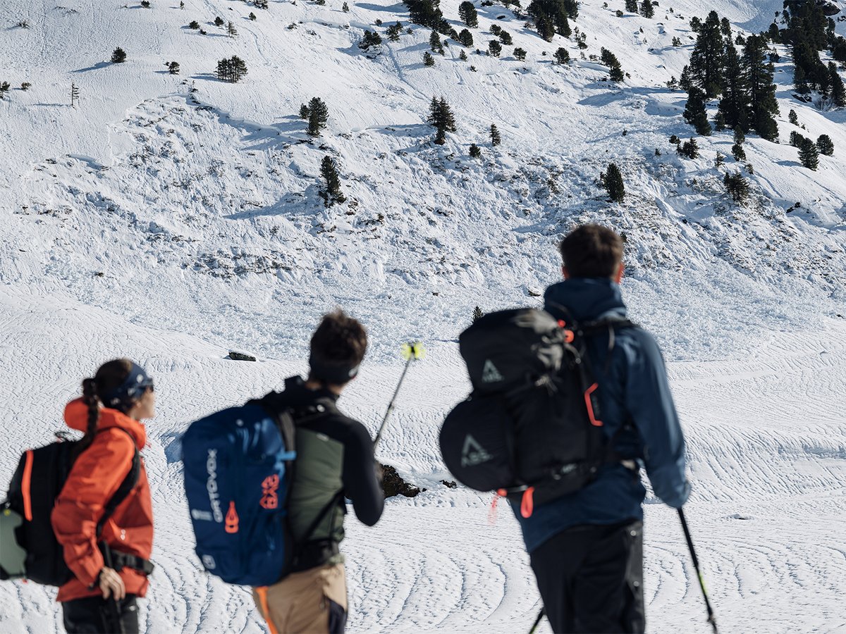 Three ski tourers looking across an avalanche debris field.