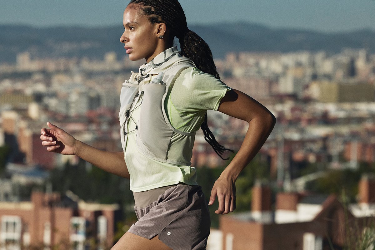 Above waist crop of runner wearing trail vest with city in the backgorund. 