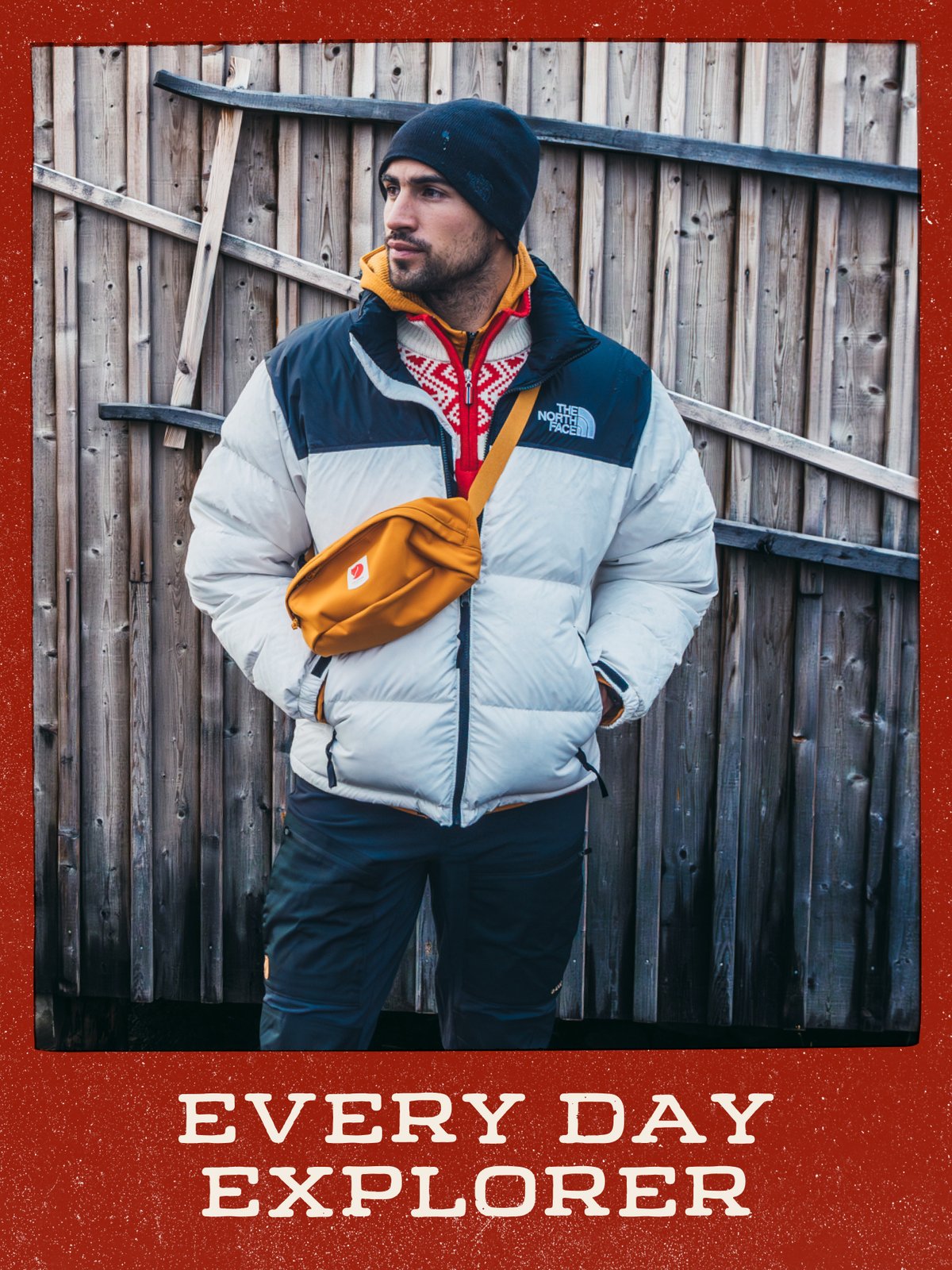 Person in a puffy jacket and beanie with an orange crossbody hip pack, standing against a weathered wooden wall: “Every Day Explorer.”
