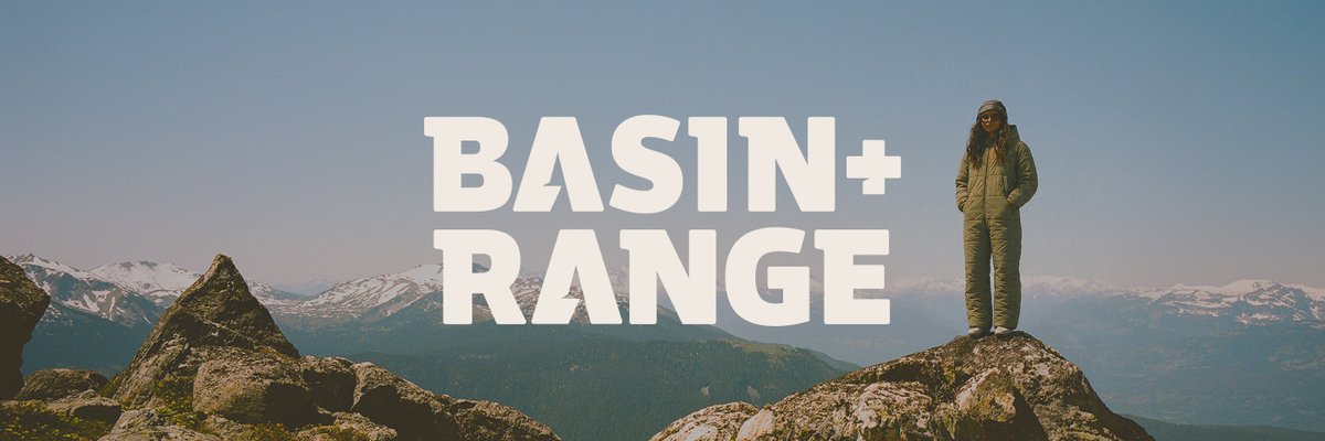 Basin and Range logo over a person in an insulated one-piece suit standing on a rocky summit with snow-capped peaks behind them.